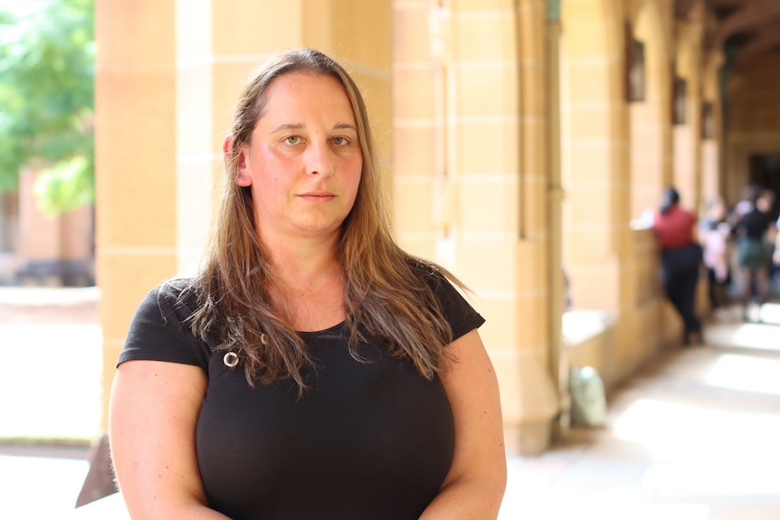 Une femme se tient dans un couloir d'un campus universitaire.