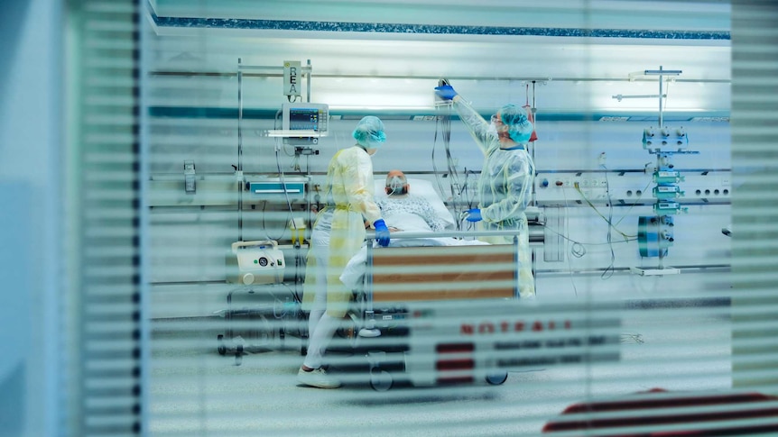 Doctors and nurses caring for patient in an ICU bed