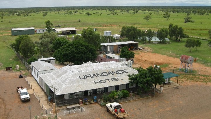 An aerial view of a country pub surrounded by paddocks, with vehicles parked out the front.