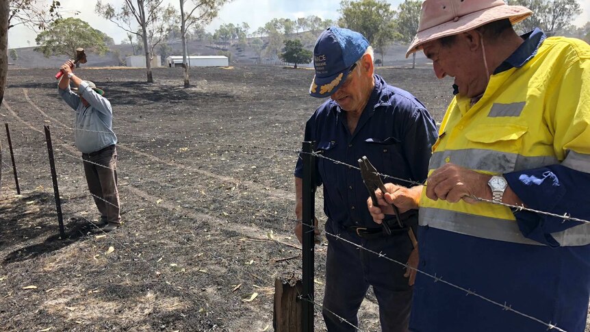 Three men fix fences on a burnt out property at Woolooga.