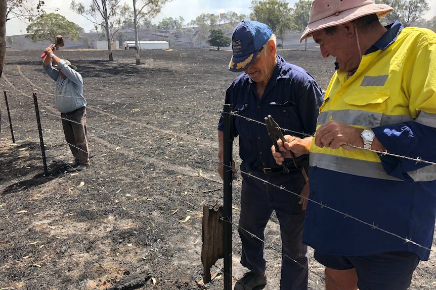 Three men fix fences on a burnt out property at Woolooga.