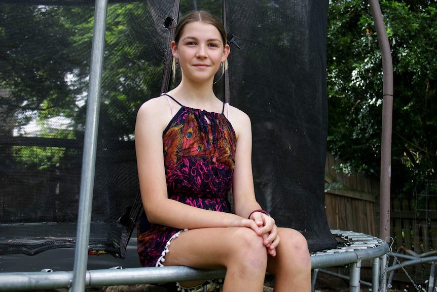 A girl sitting on the edge of a trampoline