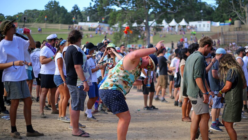 Man holds two cans in one hand and dances at Byron Falls Festival