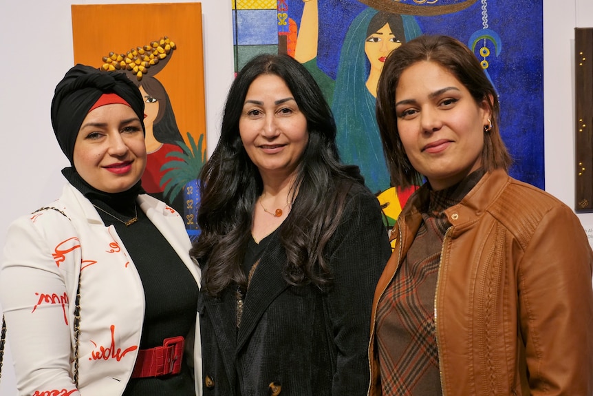 Three women pose for the camera at a function. 