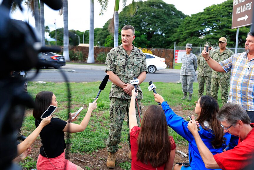 US Navy Admiral Robb Chadwick is dressed in military fatigues and speaks to reporters on a street lawn.