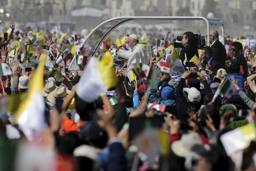 Pope Fracis, riding in his 'Popemobile', waves to a crowd of hundreds of thousands of people.