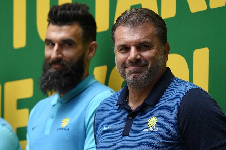 Mile Jedinak and Ange Postecoglou smile on stage at Martin Place during a public reception for the Socceroos.