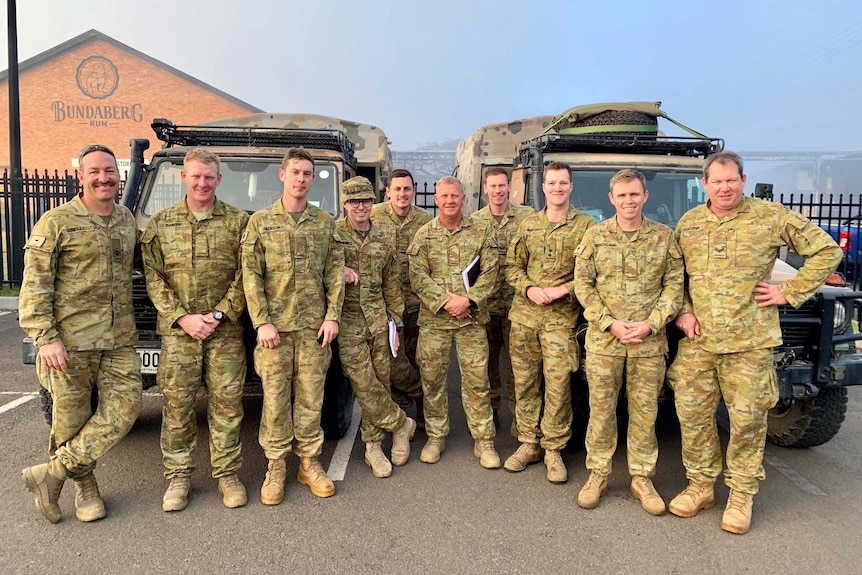 Male army officers stand in front of their vehicles at the Bundaberg Rum Distillery