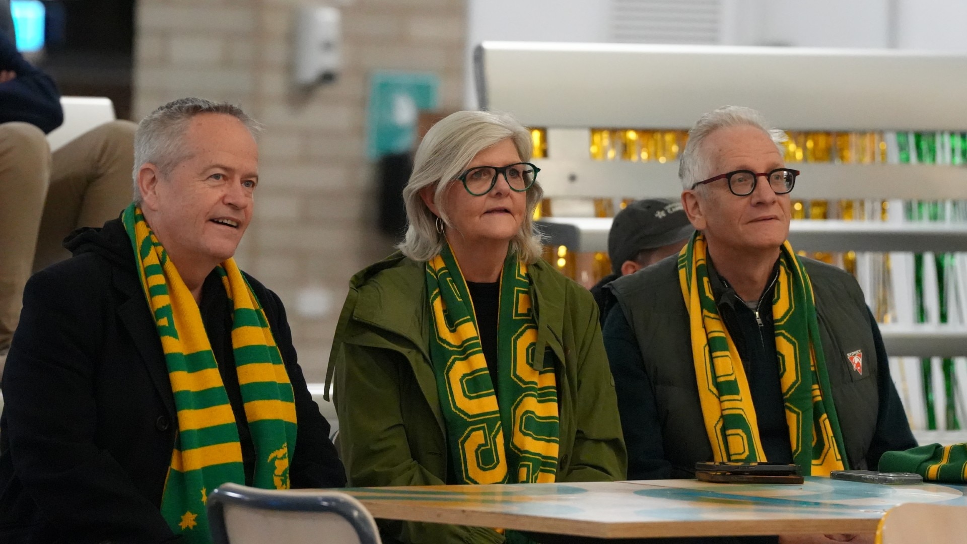 Three people wearing Socceroos scarfs.