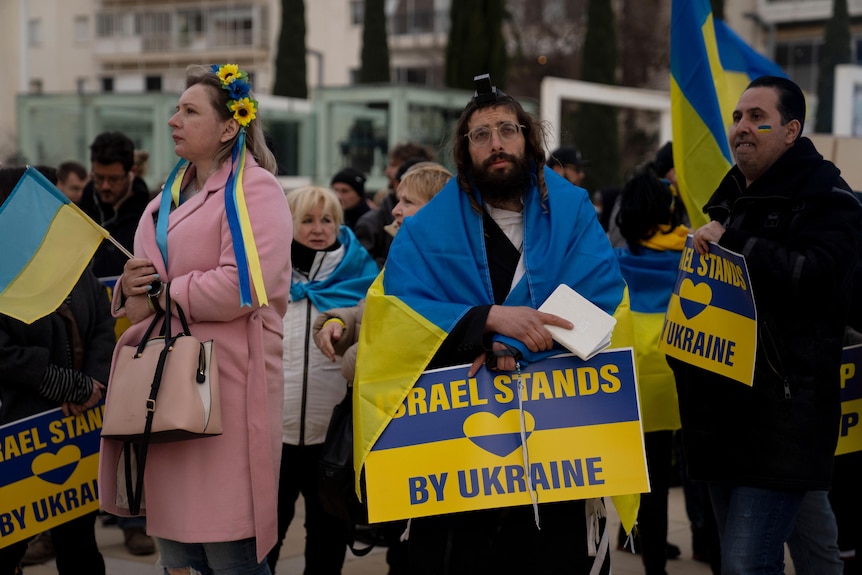 People holding banners and flags in yellow and blue gather to show their support for Ukraine.