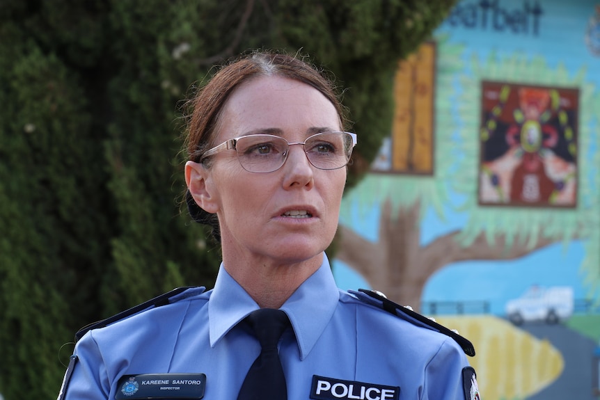 A police woman in uniform with glasses stands speaking at a press conference