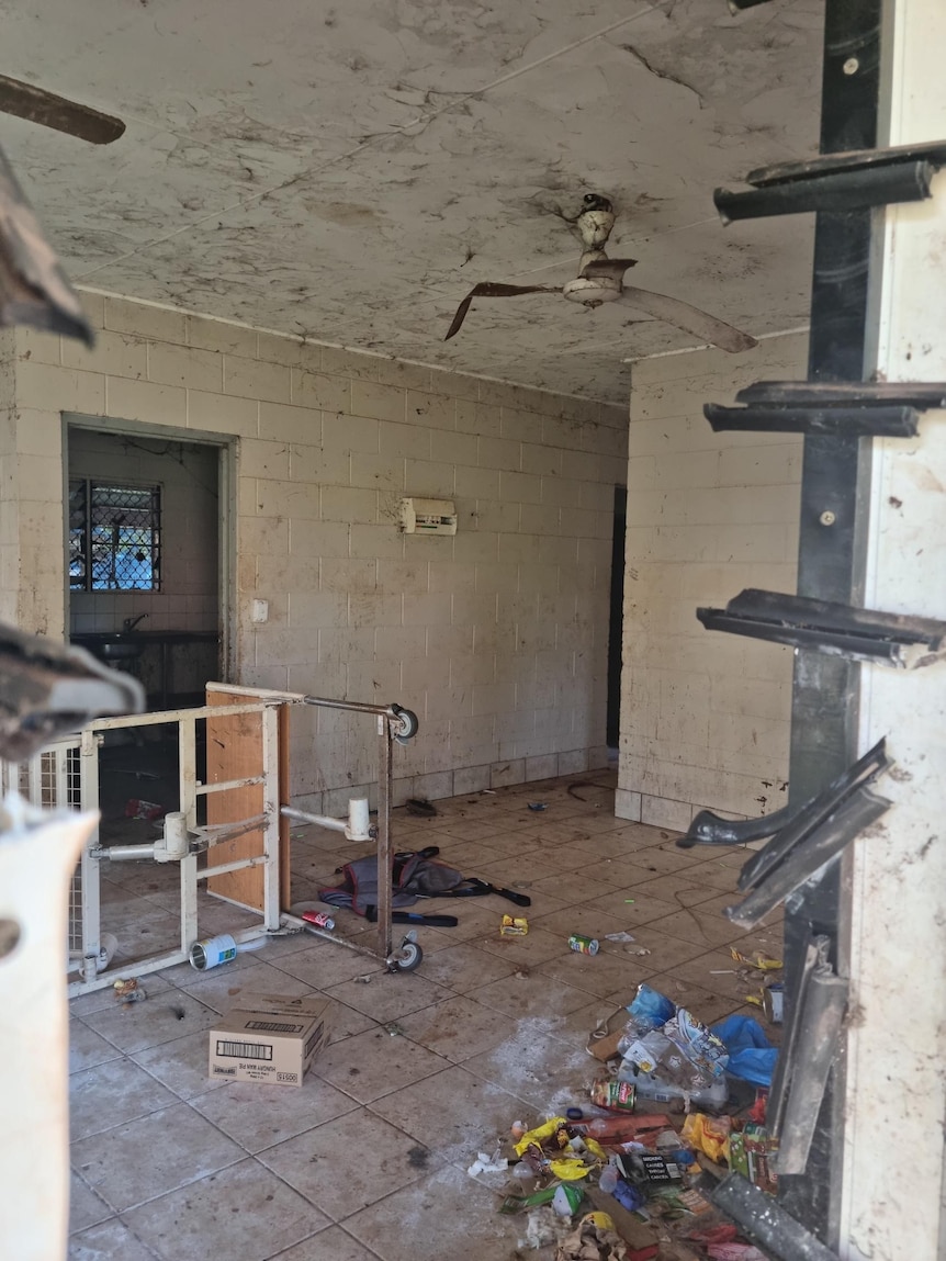 A photograph of a house or shop which has been trashed. Shelves are broken and rubbish is on the ground.