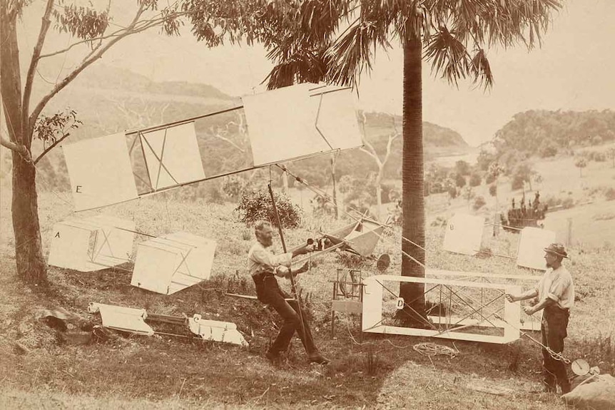 Historical photo of two men preparing to launch box kites to fly