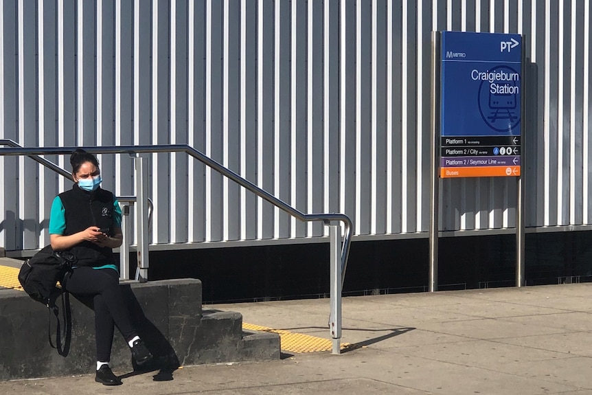 A woman sits on concrete steps outside the station entrance