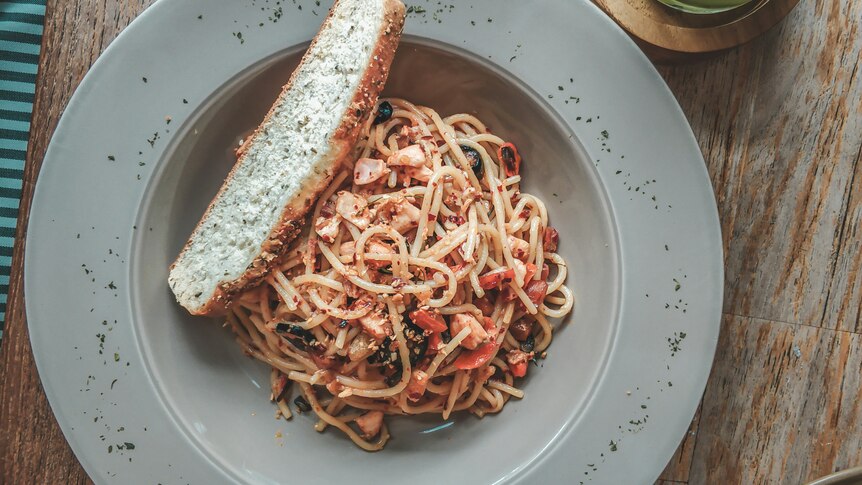 a bowl of pasta with a piece of bread