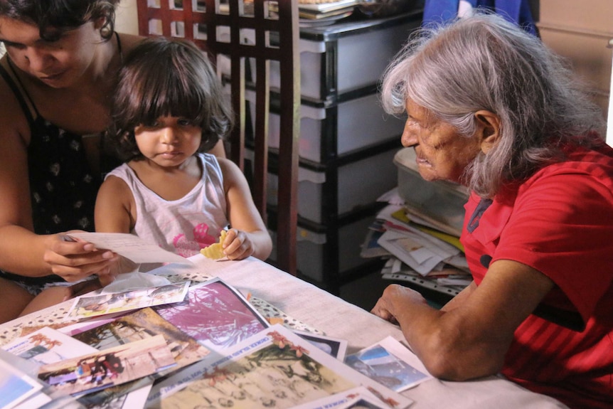 Claire Henty-Gebert showing pictures to family while sitting at a table