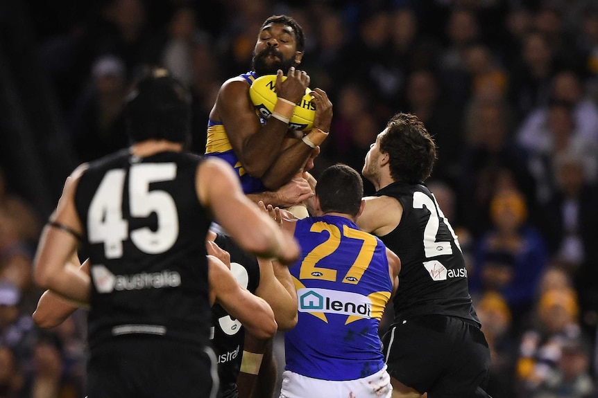 An AFL player leaps highest and holds on to a mark as other players look up at him.