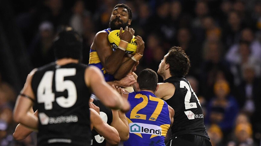 An AFL player leaps highest and holds on to a mark as other players look up at him.