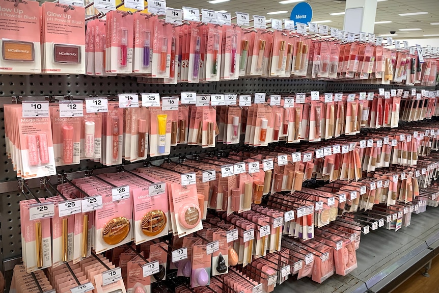 Rows of light pink and white packaged beauty products in a store.