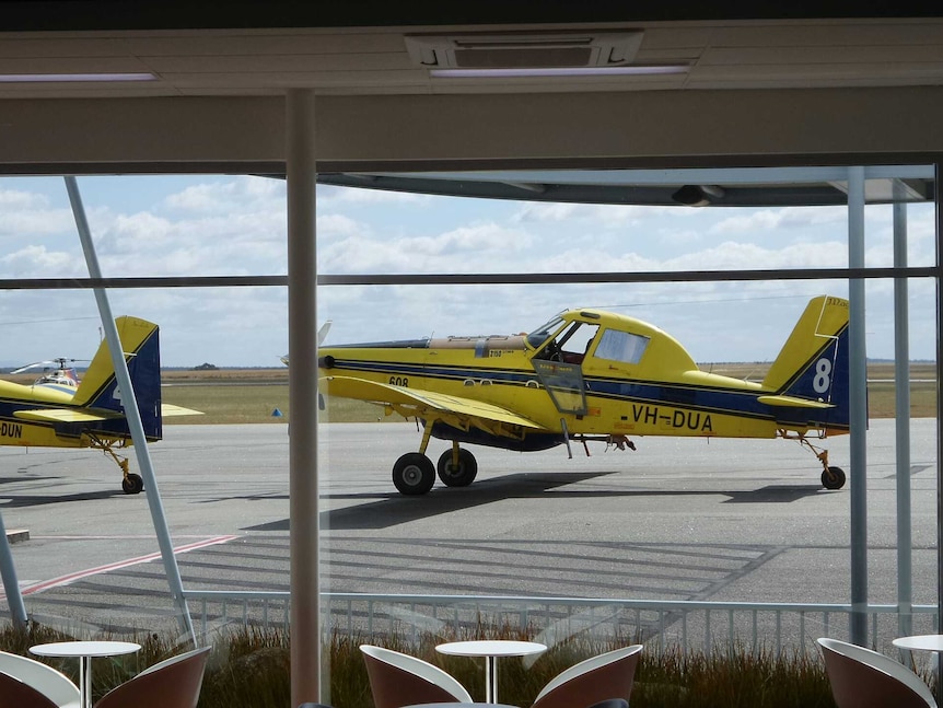 A yellow waterbomber parked on a runway