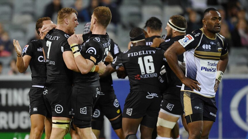 The Brumbies' Tevita Kuridrani reacts as Sharks players celebrate Lukhanyo Am's winning try.