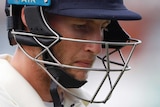 Joe Root walks off with his helmet on with a sombre expression on his face
