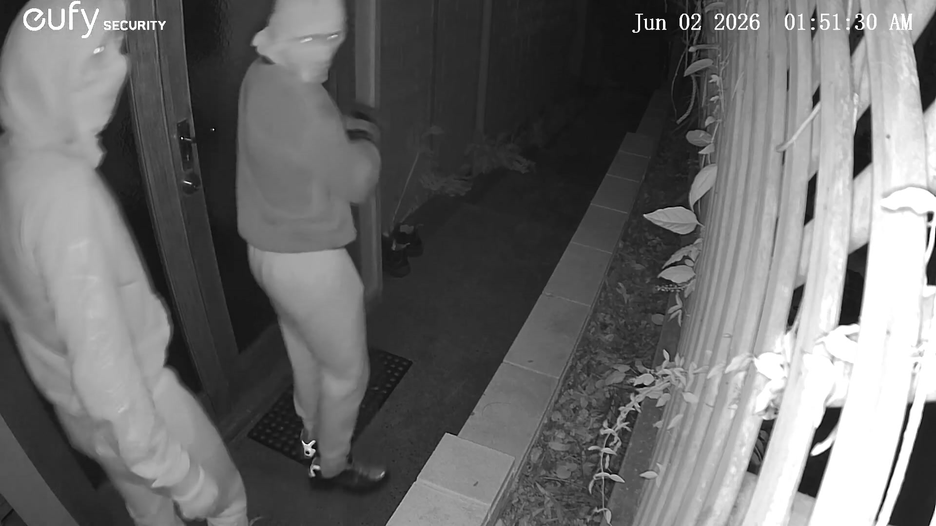 Two males with face masks standing at a front door