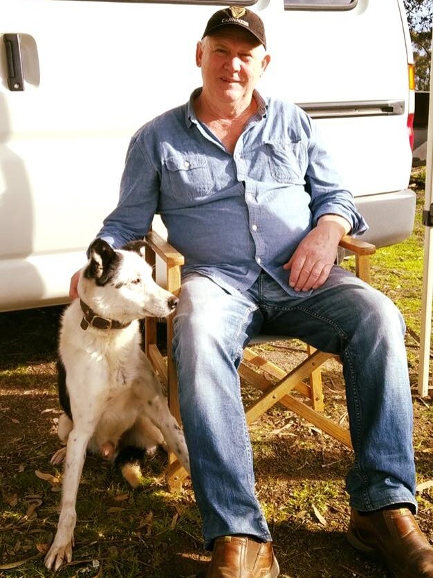 Barry Paton, sitting, pats one of his working dogs.