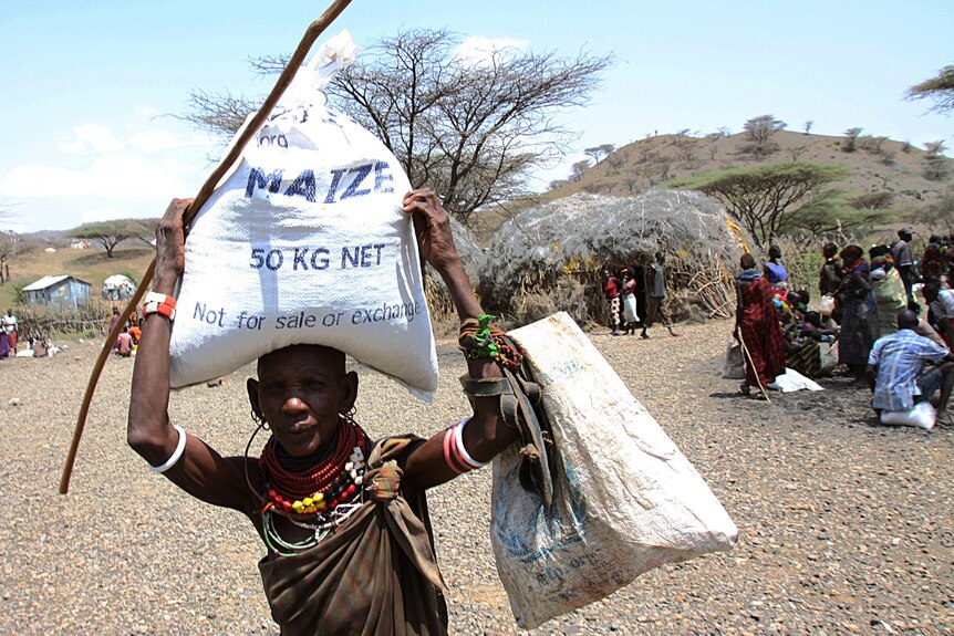 A Turkana woman walks carries food rations as she leaves a relief distribution centre at Lokitaung in Kenya.