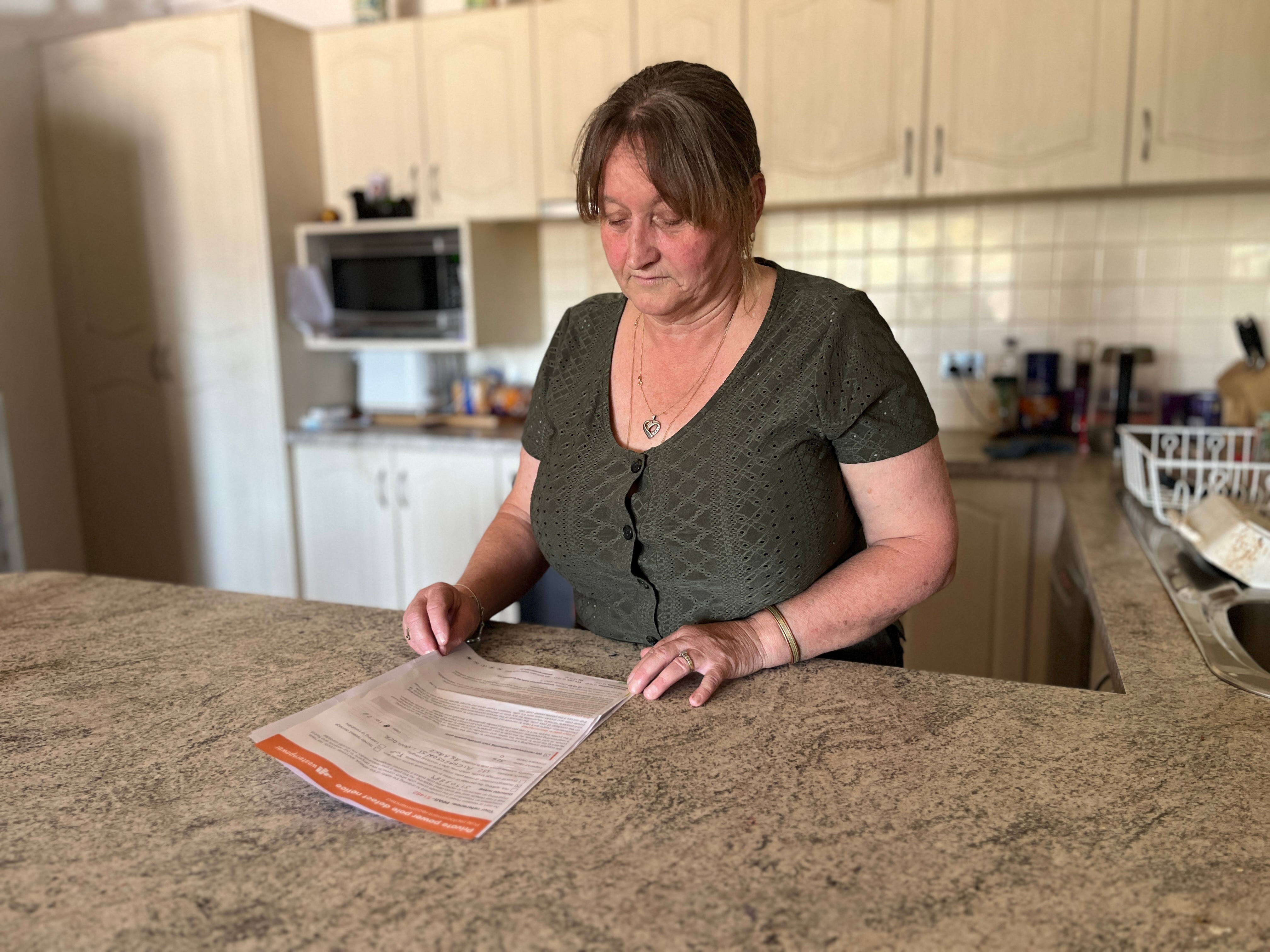 A woman in the kitchen reading a letter 