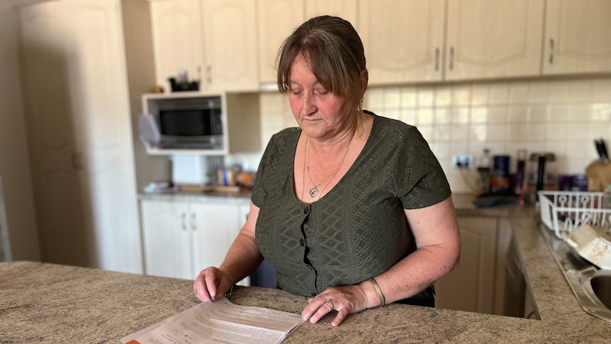 A woman in the kitchen reading a letter 