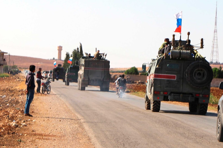 Russian trucks fly Russian flags as they patrol the Syrian borde.