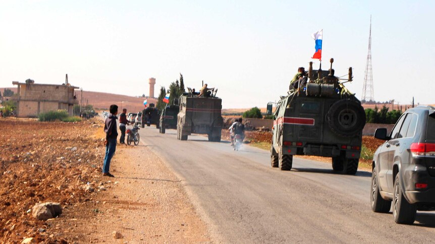 Russian trucks fly Russian flags as they patrol the Syrian borde.