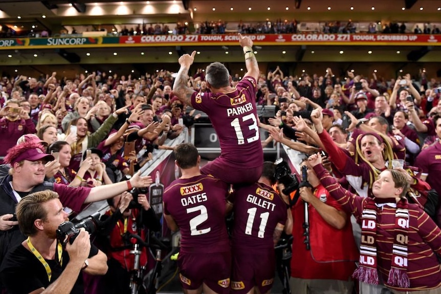 A man is on shoulders as he is led off a field with fans surrounding him.