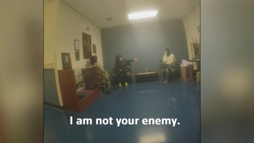A image from a bodycam shows a meeting between three people where one says: "I am not your enemy."