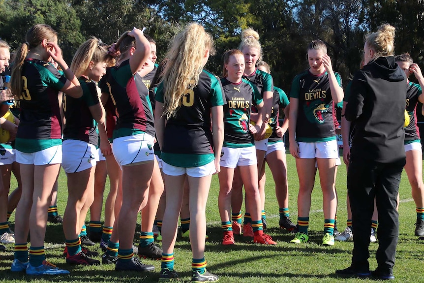 Under-15 female footballers gather to listen to their coach.