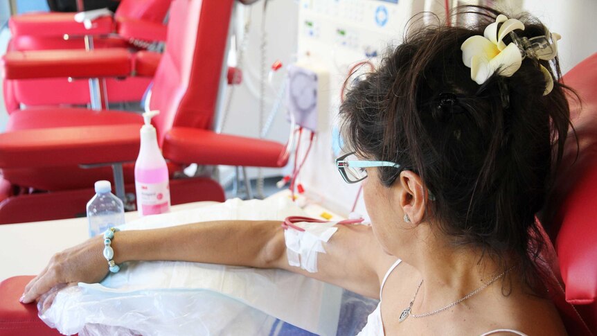 Close up of dialysis patient looking at the tubes in her arms