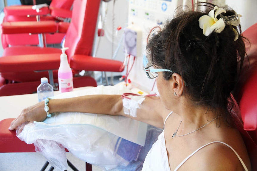 Close up of dialysis patient looking at the tubes in her arms