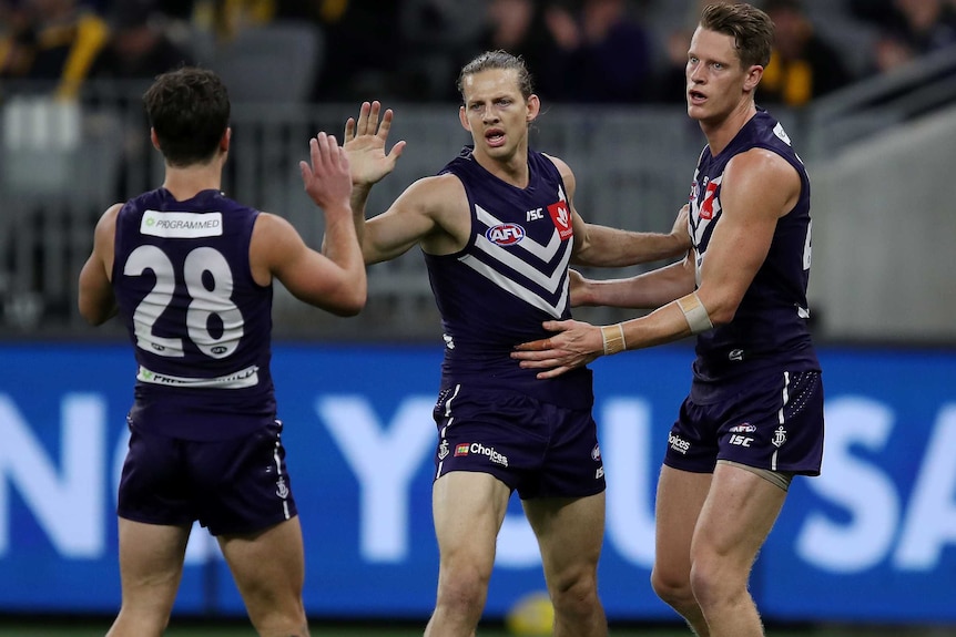 Nat Fyfe high fives one teammate and is patted on the back by another