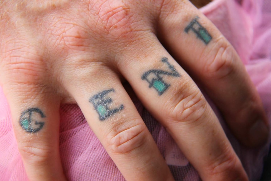 A man's hand, with the letters G, E, N, T tattooed on it.