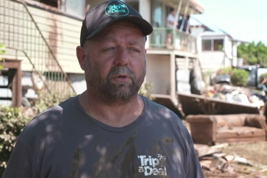 A man wearing a muddy t-shirt and cap.