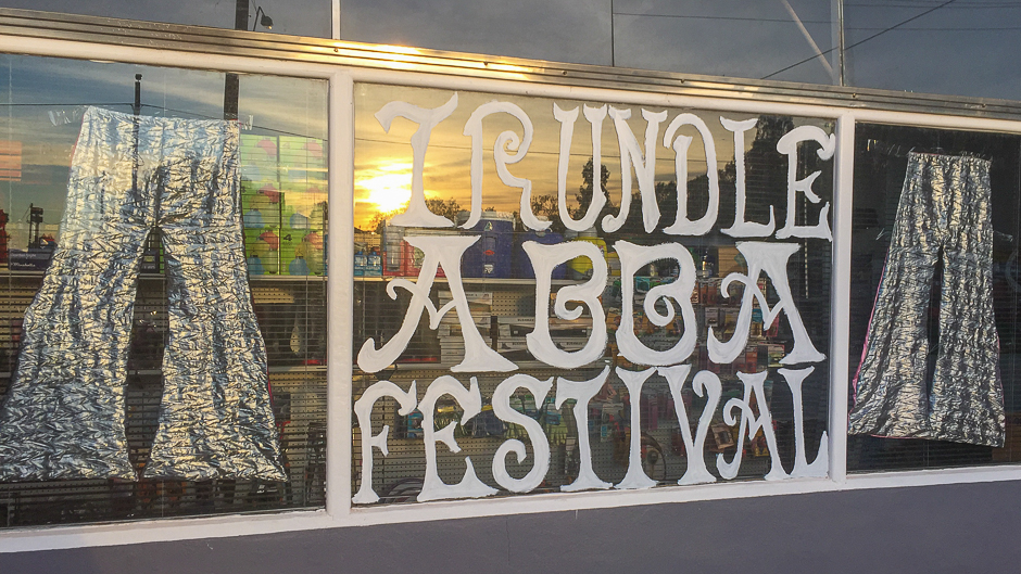 A shop window with silver flares hanging in it and the words Trundle ABBA festival painted on