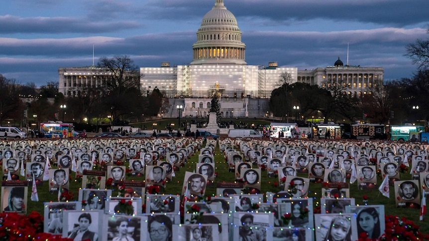 The US Capitol is seen behind a vigil showing photos on a lawn of Iranians allegedly killed by their government.