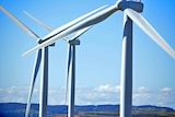 A close up of wind turbine blades, with a blue sky in the background.