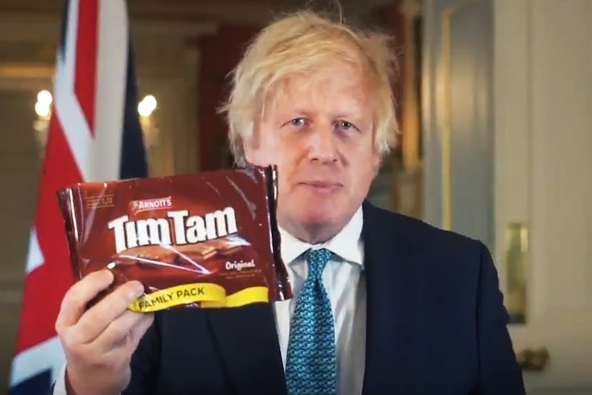 Boris Johnson holding a packet of Tim Tams