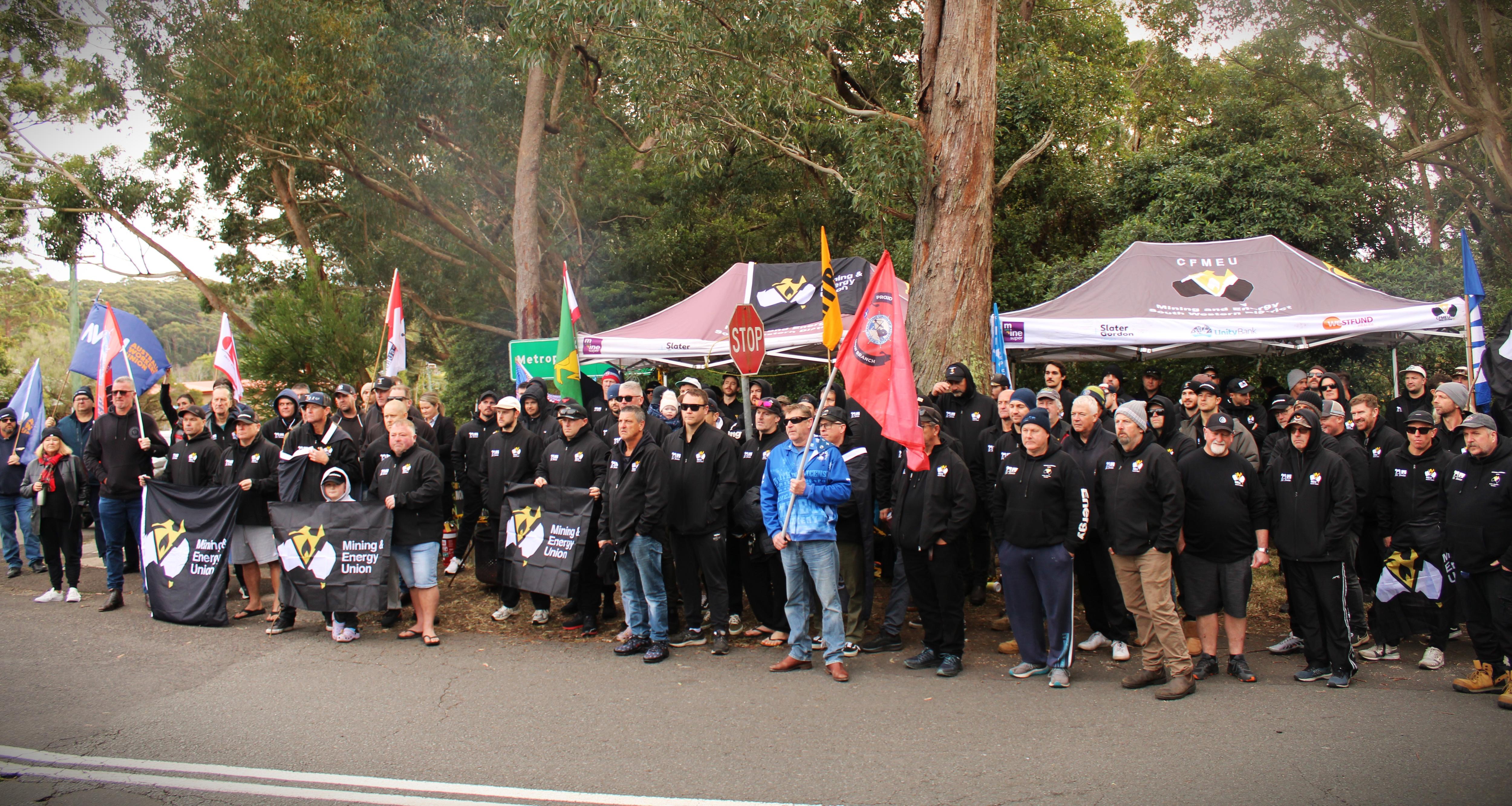 Imagen de una gran multitud con banderas y pancartas al costado de un camino