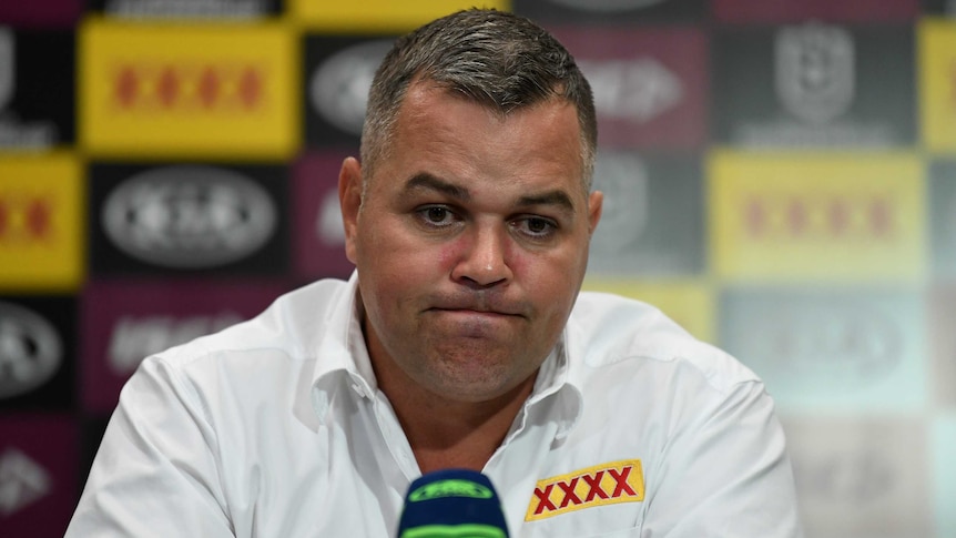 A dejected NRL coach sits with a microphone in front of him at a post-match press conference.