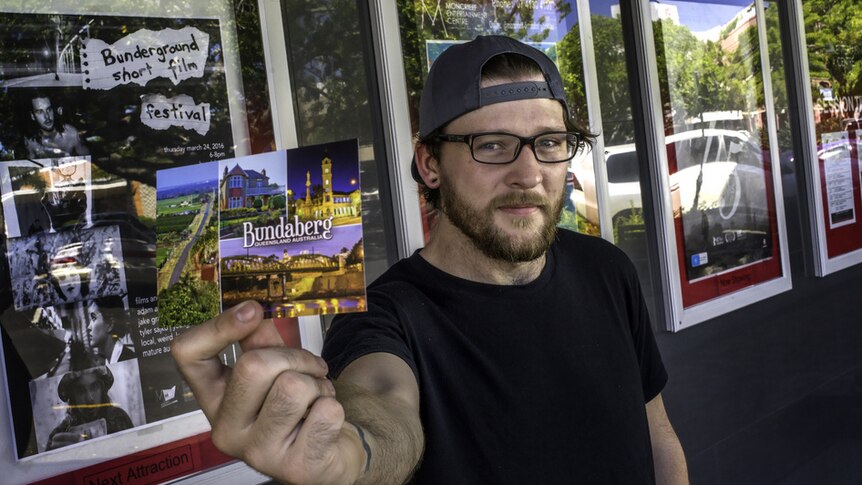 James Latter holds up and 80 cent postcard.  It was the only prop he had to buy to produce his short film in Bundaberg.