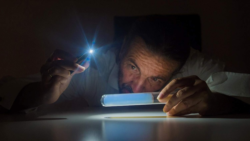 a man in dark holding test tube