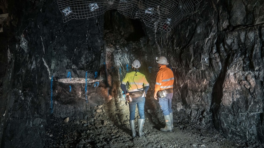 Two underground miners standing in the dark underground. 